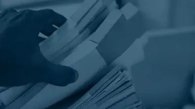 Hand hält Stapel papierbasierter Dokumente zur professionellen Digitalisierung von Akten und Archiven.